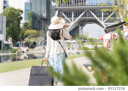 Back view of a young woman pulling a suitcase and sightseeing in Nagoya Back view of a young woman pulling a suitcase and sightseeing in Nagoya 95137258