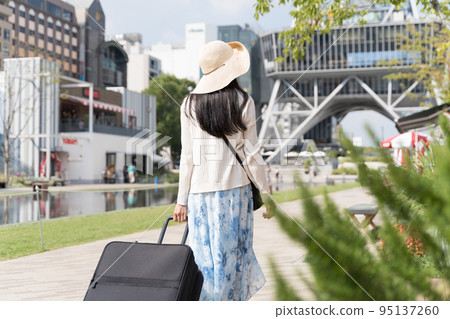 Back view of a young woman pulling a suitcase and sightseeing in Nagoya 95137260