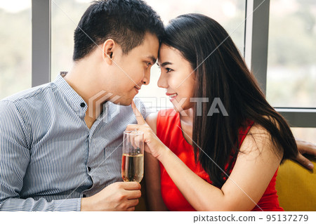 Smile asian lover couple male hand hold a champagne. She touch finger on man face. 95137279
