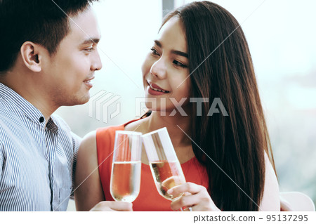 Smile asian lover couple man and woman hand hold a champagne drink and cheer. Smile asian lover couple man and woman hand hold a champagne drink and cheer. 95137295