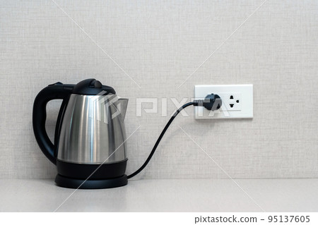 Silver metal electric kettle for boiling water and making tea on a table. Household kitchen appliances for makes hot drinks Silver metal electric kettle for boiling water and making tea on a table. Household kitchen appliances for makes hot drinks 95137605