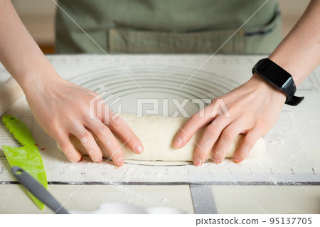 Woman hands with electronic fitness bracelet cooking homemade cakes on silicone baking mat 95137705