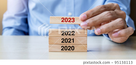 2023 block over 2022 and 2021 wooden building on table background. Business planning, Risk Management, Resolution, strategy, solution, goal, New Year New You and happy holiday concepts 95138113