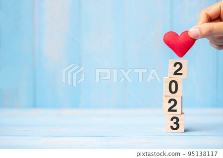 hand holding red heart shape over 2023 wooden cubes on blue table background with copy space for text. Business, Resolution, New Year New Yo hand holding red heart shape over 2023 wooden cubes on blue table background with copy space for text. Business, Resolution, New Year New Yo 95138117