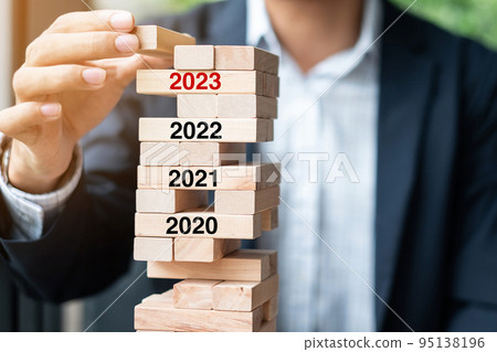 2023 year Goals, Business planning, Risk Management, Solution and strategy Concepts. Businessman hand placing or pulling wooden block on the tower 95138196