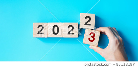 hand holding wooden cube block with 2023 text on blue background. Resolution, plan, review, goal, start and New Year holiday concepts 95138197