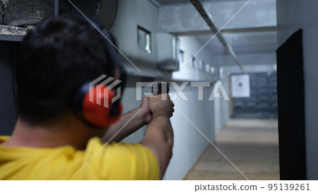 Man shooter in headphones shooting at target 95139261