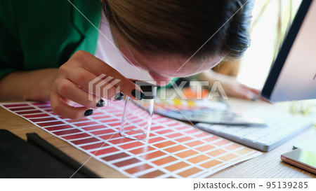 Graphic designer looking at colors samples through loupe Graphic designer looking at colors samples through loupe 95139285