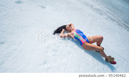 Caucasian woman in a swimsuit sunbathes on the snow in winter. Caucasian woman in a swimsuit sunbathes on the snow in winter. 95140462