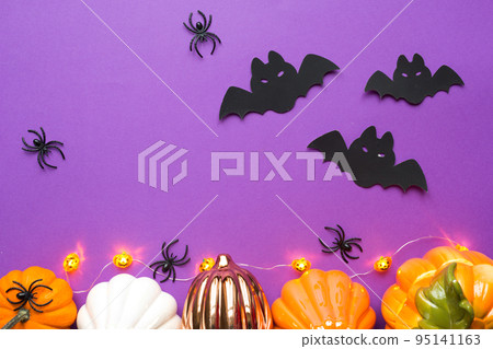 Halloween backgrounds of white, orange and gold pumpkins, spiders and black bats on a purple background with cobwebs and terrible scenery. Horror and a scary holiday with copy space 95141163