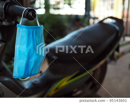 The mask is hanging from the motorcycle to be ready at all times. At irregular intervals. new normal concept. COVID-19 95143601