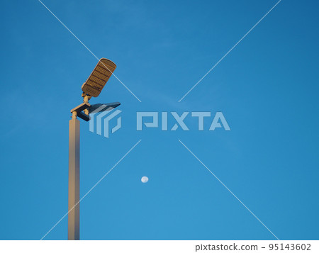 The spotlight tower on the background is a blue sky And there is a small moon in the middle 95143602