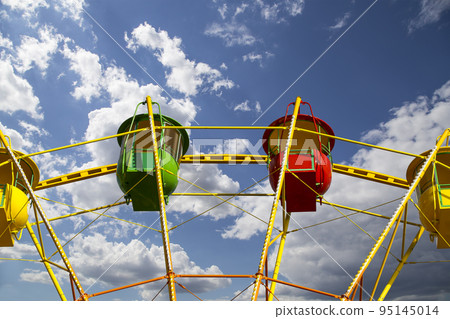 Attraction (carousel) ferris wheel on the background of the cloudy sky Attraction (carousel) ferris wheel on the background of the cloudy sky 95145014