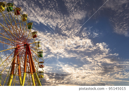 Attraction (carousel) ferris wheel against the background of a romantic evening sky Attraction (carousel) ferris wheel against the background of a romantic evening sky 95145015