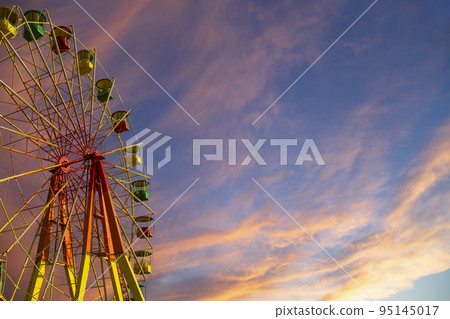 Attraction (carousel) ferris wheel against the background of a romantic evening sky Attraction (carousel) ferris wheel against the background of a romantic evening sky 95145017