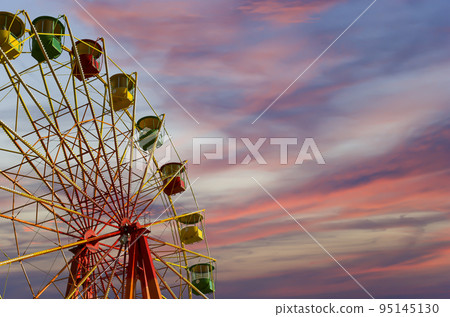 Attraction (carousel) ferris wheel against the background of a romantic evening sky Attraction (carousel) ferris wheel against the background of a romantic evening sky 95145130