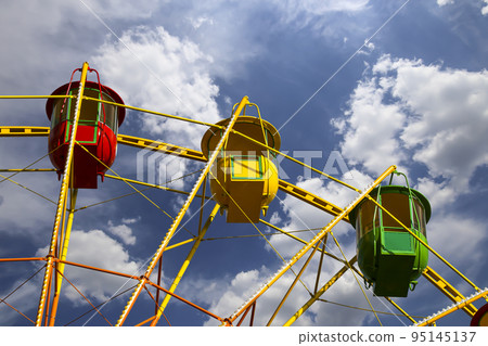 Attraction (carousel) ferris wheel on the background of the cloudy sky Attraction (carousel) ferris wheel on the background of the cloudy sky 95145137