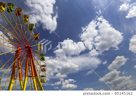Attraction (carousel) ferris wheel on the background of the cloudy sky Attraction (carousel) ferris wheel on the background of the cloudy sky 95145162