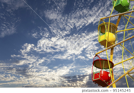 Attraction (carousel) ferris wheel on the background of the cloudy sky Attraction (carousel) ferris wheel on the background of the cloudy sky 95145245