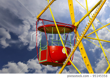 Attraction (carousel) ferris wheel on the background of the cloudy sky Attraction (carousel) ferris wheel on the background of the cloudy sky 95145358