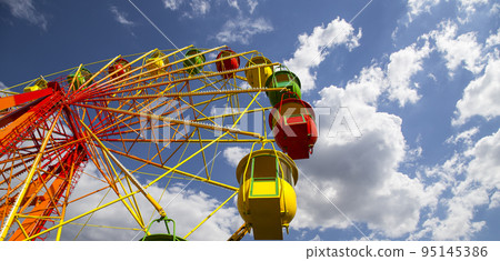 Attraction (carousel) ferris wheel on the background of the cloudy sky Attraction (carousel) ferris wheel on the background of the cloudy sky 95145386