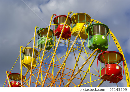 Attraction (carousel) ferris wheel on the background of the cloudy sky Attraction (carousel) ferris wheel on the background of the cloudy sky 95145399