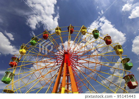 Attraction (carousel) ferris wheel on the background of the cloudy sky Attraction (carousel) ferris wheel on the background of the cloudy sky 95145443