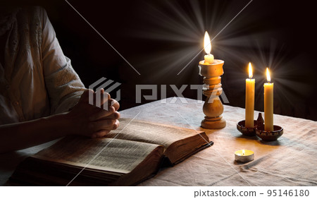 Woman reading the Bible by candlelight Woman reading the Bible by candlelight 95146180