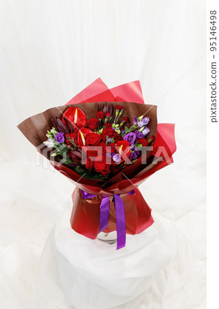Beautiful large bouquet composed of red and purple flowers on stand on white fabric background. 95146498