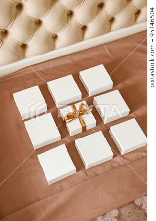 Set of small minimalist gift boxes for jewelry spread out on luxury bed. 95146504