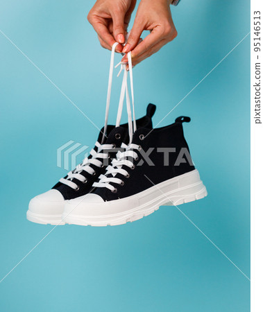 Stylish and fashionable model of black and white sneakers on blue background. 95146513