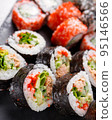 Large sushi set of various sushi rolls is served on black square metal slate. 95146566