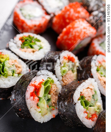 Large sushi set of various sushi rolls is served on black square metal slate. Large sushi set of various sushi rolls is served on black square metal slate. 95146566