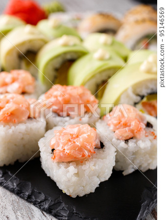 Sushi roll covered with chopped salmon and caviar is served on rectangular black slate. Sushi roll covered with chopped salmon and caviar is served on rectangular black slate. 95146569