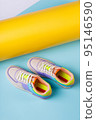 Pair of fashionable bright sports shoes for teens standing on orange-blue background. 95146590