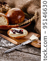 Sliced piece of freshly baked buns with butter and jam on wooden kitchen board. 95146630