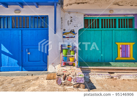 Colorful blue, green boat garage doors, Klima fishermen village, Greece. Painted and weathered wooden doorways, whitewashed walls. Colorful blue, green boat garage doors, Klima fishermen village, Greece. Painted and weathered wooden doorways, whitewashed walls. 95146906