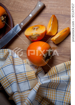Whole ripe persimmon and sliced fruit on a wooden background.. 95147457