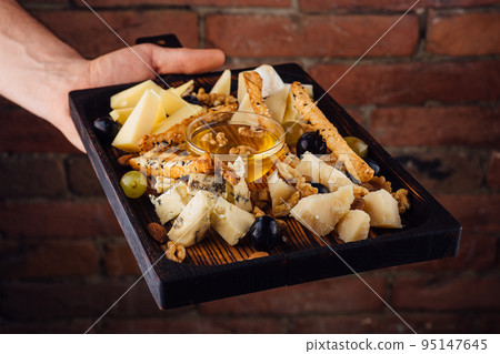Cheese plate with honey, grapes and nuts 95147645