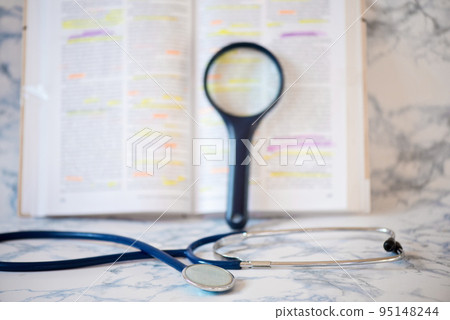 Stethoscope and magnifier near the pages of a text book Stethoscope and magnifier near the pages of a text book 95148244