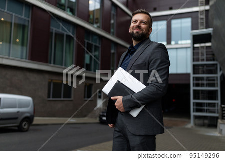 portrait of a successful adult businessman with a laptop in his hands against the background of the portrait of a successful adult businessman with a laptop in his hands against the background of the 95149296