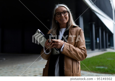 senior woman head with a laptop in her hands looks at the camera against the background of a non 95149302