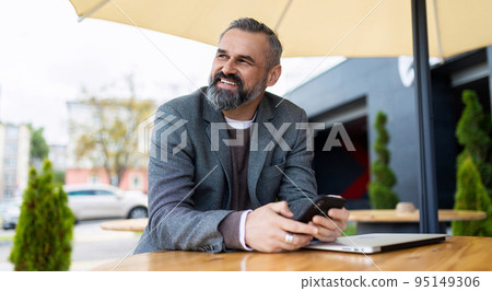 portrait of a strong gray-haired businessman next to the office with a phone in his hands 95149306