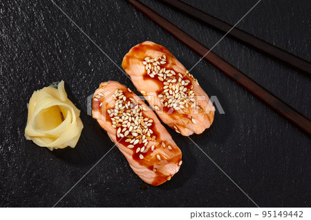 Sushi with smoked eel and sesame seeds on a black background. Japanese dish Unagi sushi. Sushi with smoked eel and sesame seeds on a black background. Japanese dish Unagi sushi. 95149442