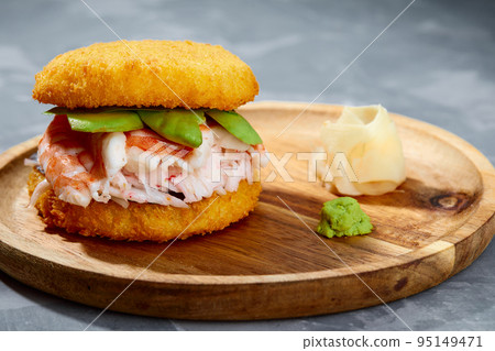 Pan-Asian cuisine concept. Japanese sushi burger made from rice bread, crab meat, avokado and wasabi sauce. Serving on wooden board. copy space 95149471