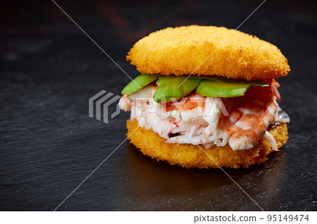 Pan-Asian cuisine concept. Japanese sushi burger made from rice bread, crab meat, avokado and wasabi sauce. Serving on wooden board. copy space 95149474