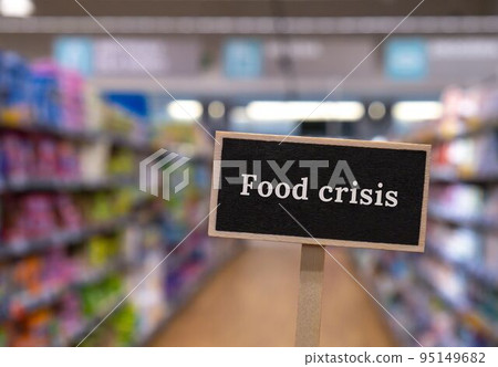 Wooden information label sign with text FOOD CRISIS against defocused store shelves message. Global hunger, inflation, high prices, increasing living expenses and poverty, financial crisis, food Wooden information label sign with text FOOD CRISIS against defocused store shelves message. Global hunger, inflation, high prices, increasing living expenses and poverty, financial crisis, food 95149682
