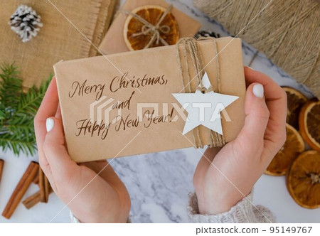 Merry Christmas and Hippy New Year Inspiration joke quote phrase Woman making Box with New Year's gifts, wrapped in craft paper and decorated with fir branch. Holidays and Gifts concept. Handmade Eco Merry Christmas and Hippy New Year Inspiration joke quote phrase Woman making Box with New Year's gifts, wrapped in craft paper and decorated with fir branch. Holidays and Gifts concept. Handmade Eco 95149767