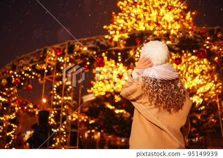 Young woman walks through the night winter city. Light around. Winter fashion, holidays, rest. Young woman walks through the night winter city. Light around. Winter fashion, holidays, rest. 95149939