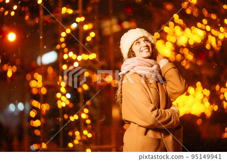 Young woman walks through the night winter city. Light around. Winter fashion, holidays, rest. 95149941